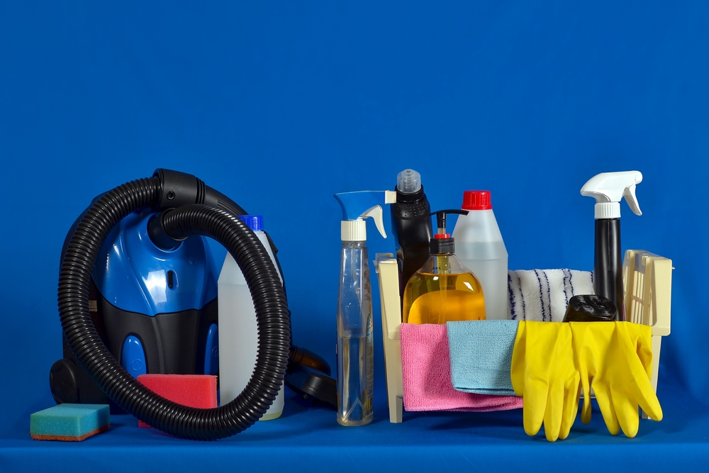 A collection of sofa cleaning supplies, including a vacuum cleaner, cleaning sprays, sponges, gloves, and microfiber cloths, arranged against a blue background.