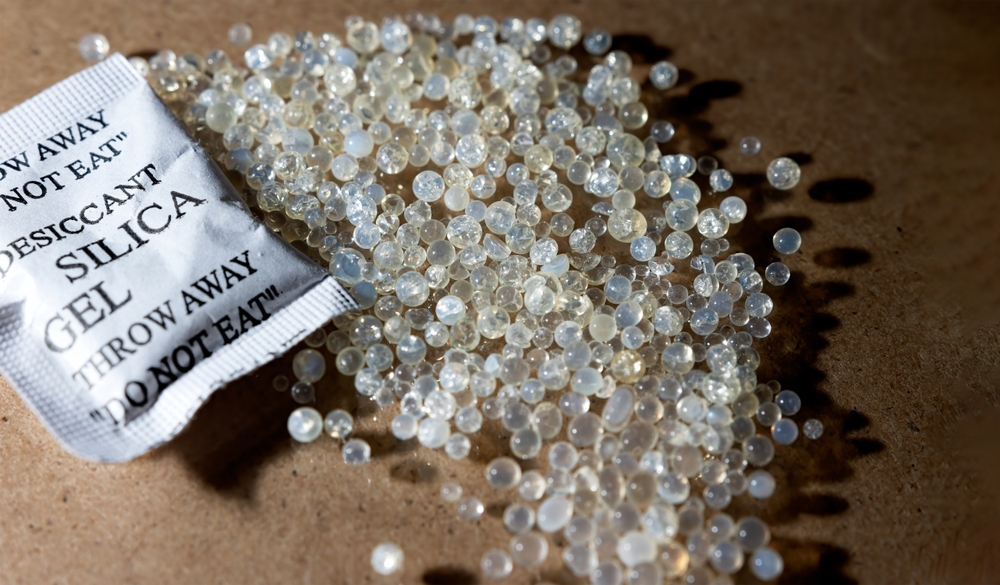 Spilled silica gel beads from a torn packet labeled 'DO NOT EAT', used as a desiccant to dehydrate and kill bed bugs effectively.
