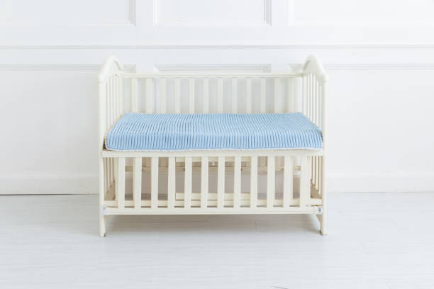 Neutral-colored baby crib with a blue striped mattress in a clean and minimalistic nursery�setting.