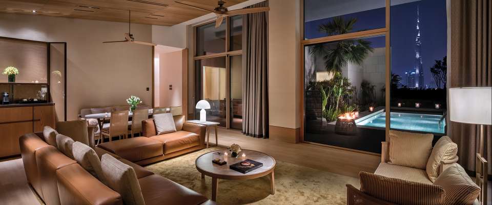 The luxurious interior of a furnished 3BHK villa in Dubai features a modern living room, dining area, and private pool with a city skyline view, ideal for deep cleaning services.