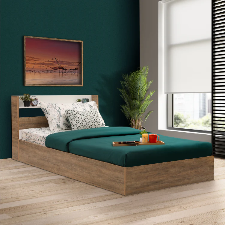 Modern wooden single bed with green bedding and decorative pillows, placed in a cozy room with a dark teal wall, a plant, and a framed artwork above the bed.
